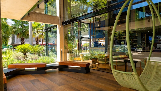 A modern interior with wooden flooring, a hanging chair, and a view of the outdoors through large windows. - Ibis Styles Porto Alegre Moinhos de Vento (Porto Alegre)