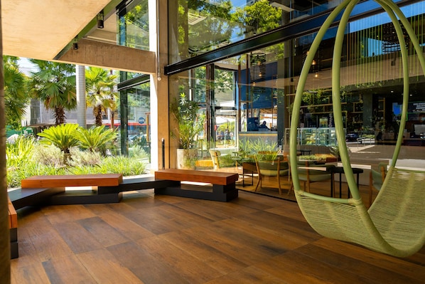 Un interior moderno con suelo de madera, un sillón colgante y vistas al exterior a través de amplios ventanales.