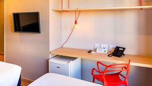 A hotel room with a bed, a desk with a phone, a small fridge, and a TV mounted on the wall. - Ibis Styles Porto Alegre Moinhos de Vento (Porto Alegre)