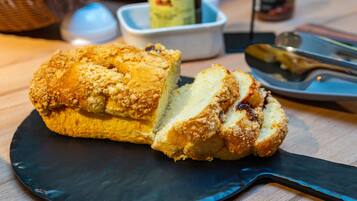 A loaf of bread on a dark plate with a knife and a small bowl in the background.