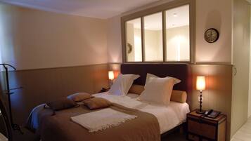 A neatly made bed with white and brown bedding, a bedside lamp, and a nightstand with a phone.