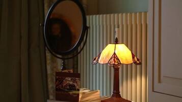 Une table de chevet avec une lampe, un miroir et une pile de livres.