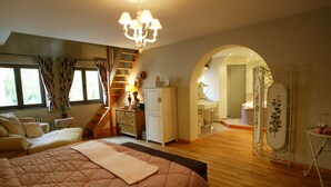 A bedroom with a large bed, a dresser, a vanity, and a staircase leading to an upper level. - Charmehotel Manoir Ogygia (Poperinge)