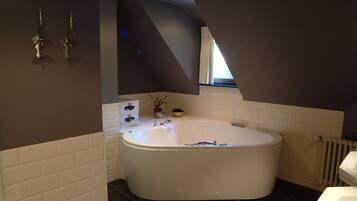 A modern bathroom with a freestanding bathtub, white tiled walls, and a window providing natural light.