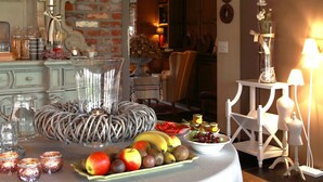 A dining table with a white tablecloth, fruit bowl, candles, and decorative items. - Charmehotel Manoir Ogygia (Poperinge)