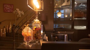 A bar area with two glass jars filled with candies, a staircase, and a window with blinds. - Charmehotel Manoir Ogygia (Poperinge)