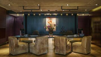 A reception area with a desk, two chairs, a floral arrangement, and a Hilton sign.