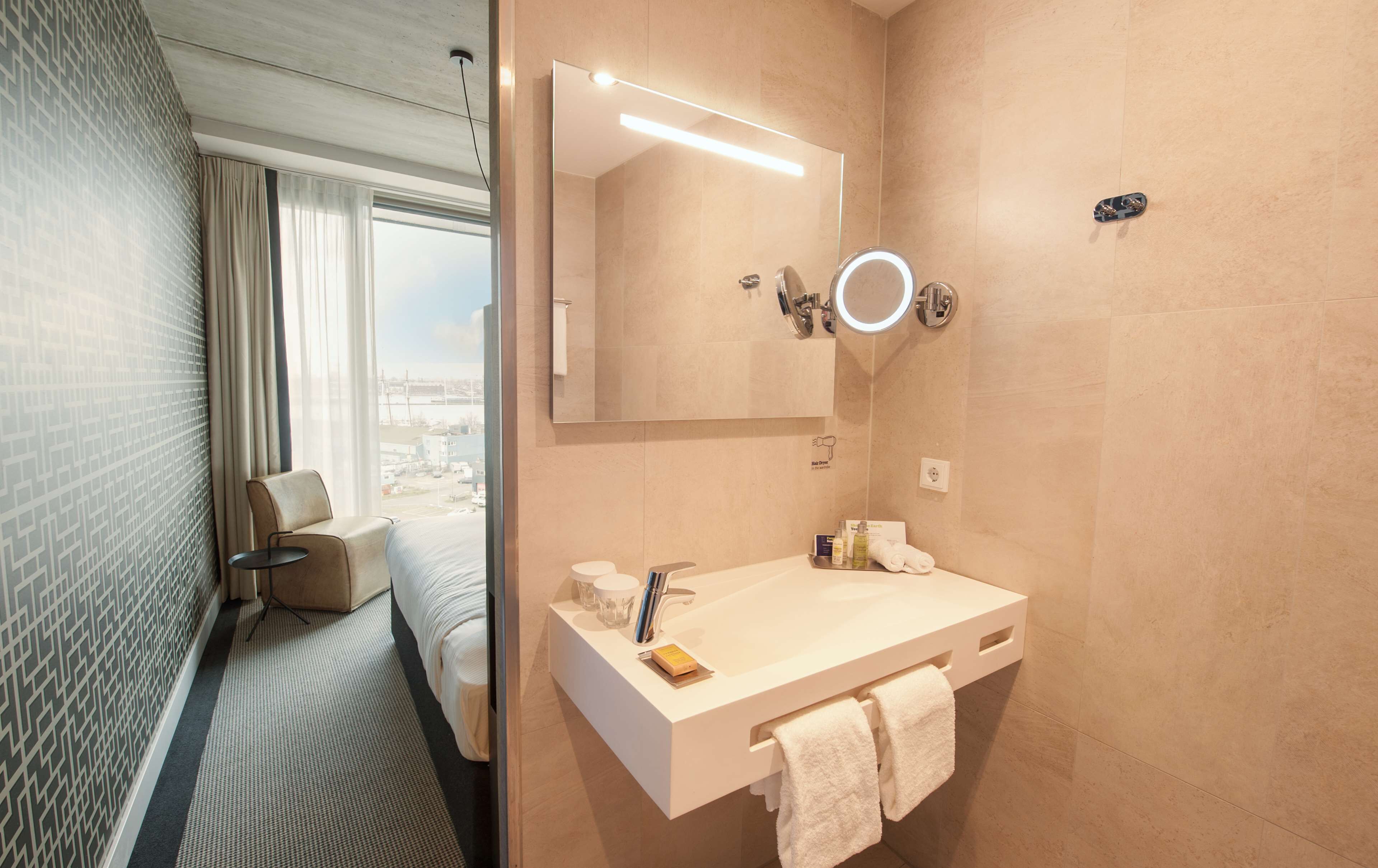 A modern bathroom with a large mirror, a sink, and a towel rack.
