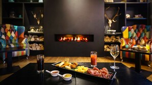 Una habitación acogedora con chimenea, sillones de colores y una bandeja de aperitivos y bebidas.