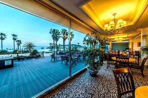 Habitación de hotel con balcón grande, mobiliario de exterior y vistas al mar.