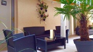 A patio area with wicker furniture, potted plants, and a large palm tree.