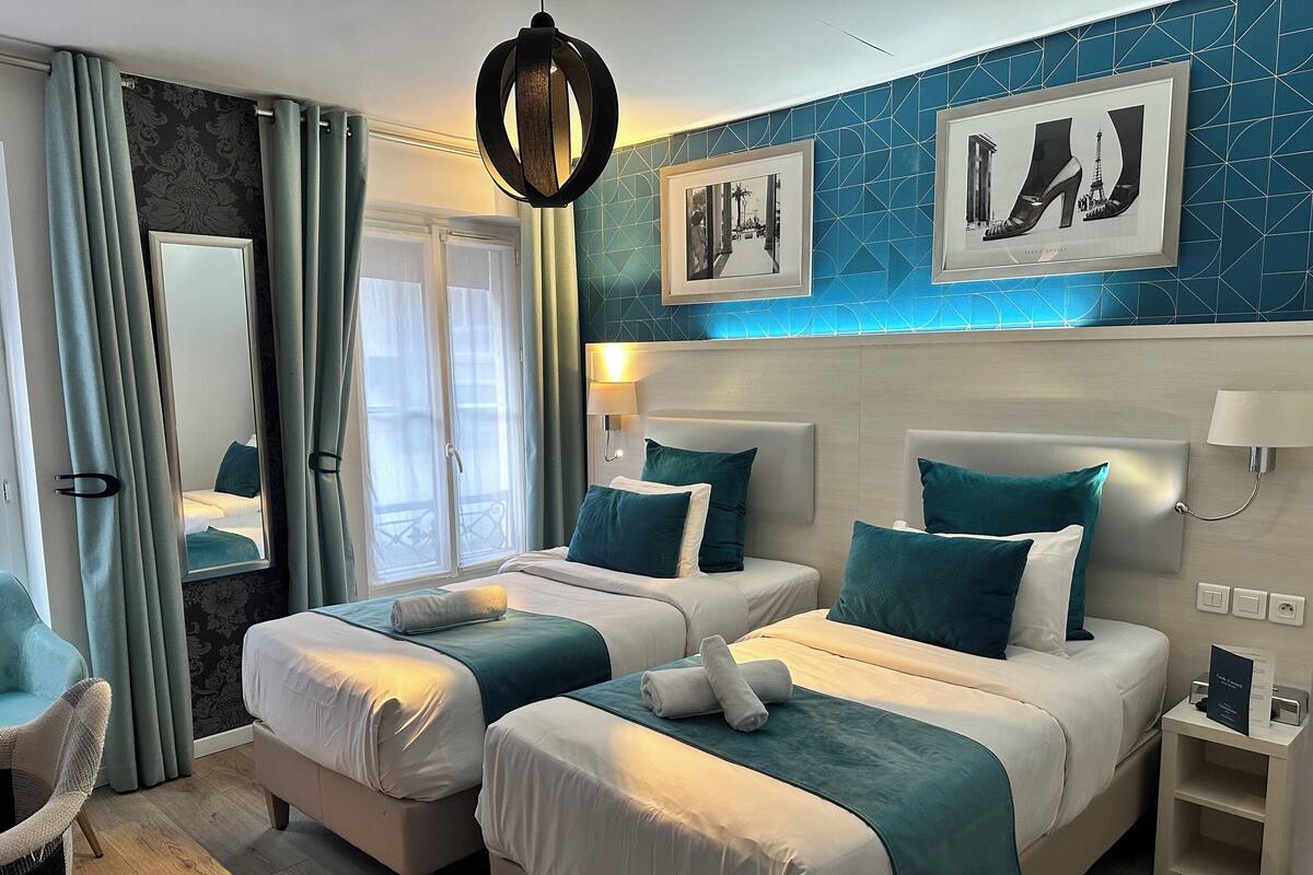 A hotel room with two beds, a large mirror, and artwork on the wall.