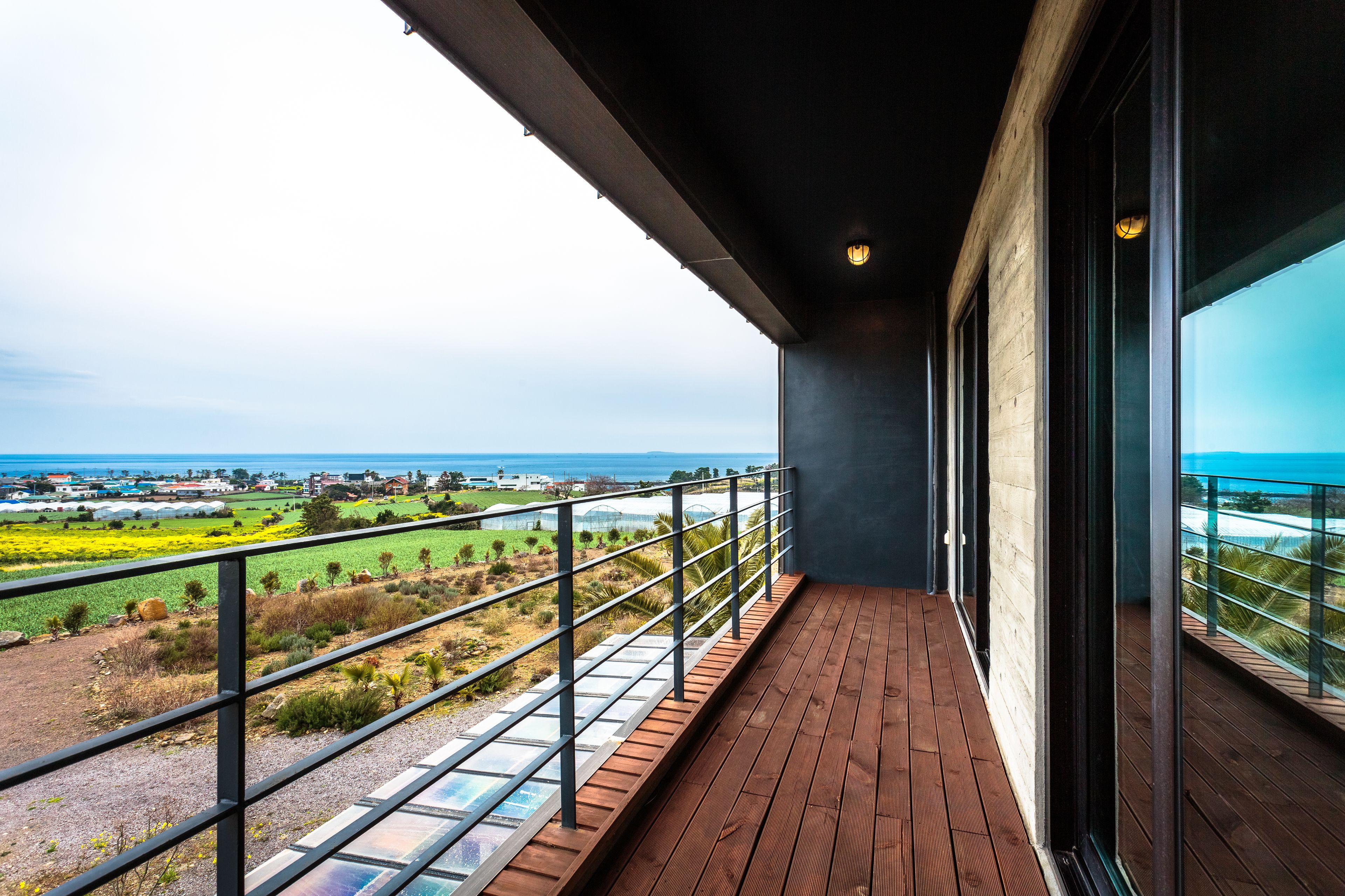Un balcone con vista su un paesaggio costiero, che comprende campi e una costa in lontananza.