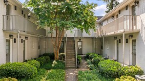 A courtyard with a central staircase, surrounded by white buildings with balconies and small windows. - BCA Furnished Apartments (Atlanta)