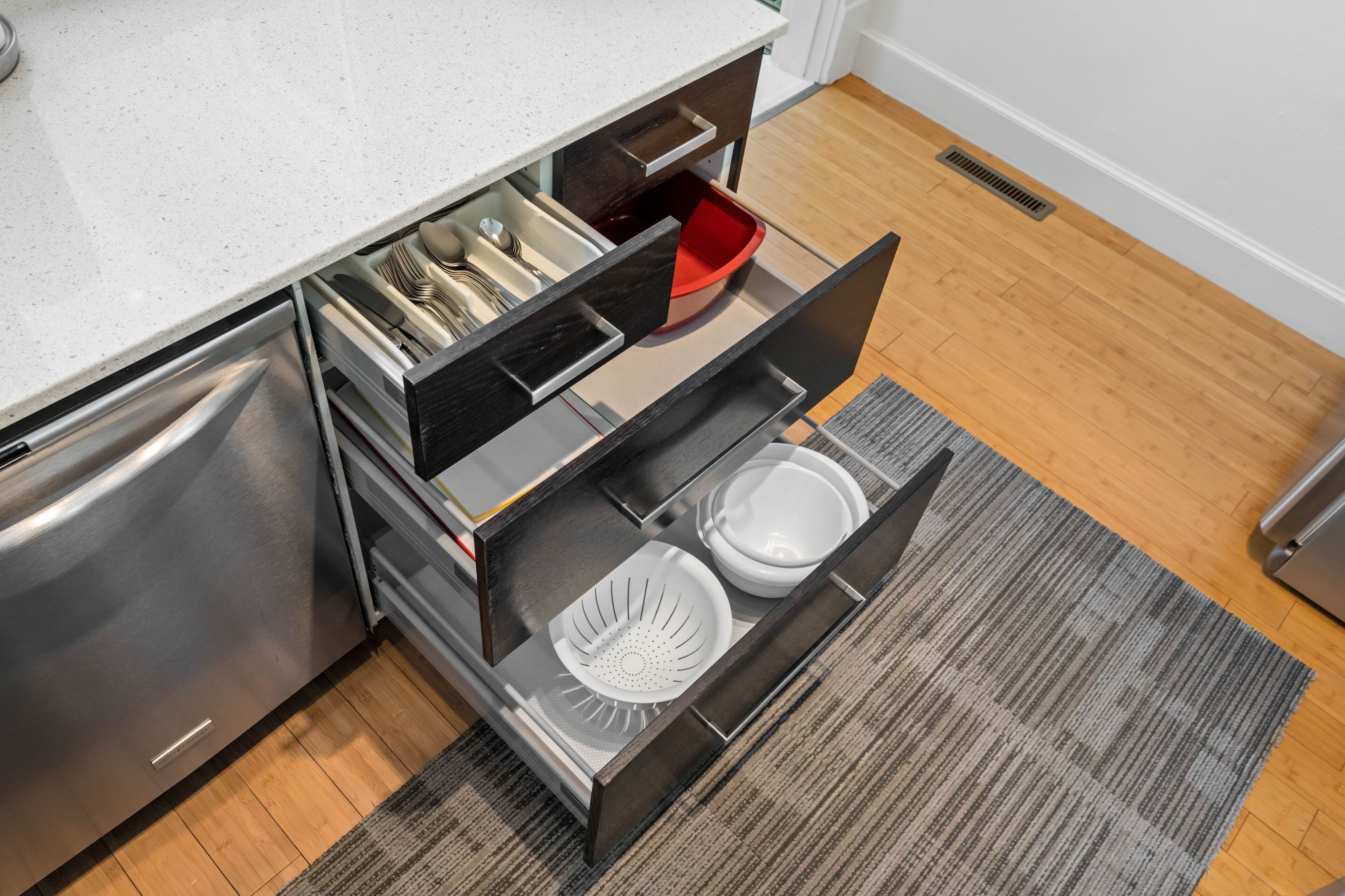 A kitchen with a stainless steel refrigerator, a white countertop, and a built-in dishwasher.