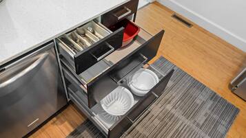A kitchen with a stainless steel refrigerator, a white countertop, and a built-in dishwasher.