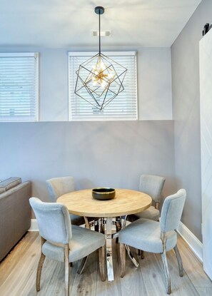 A dining area with a round wooden table, six chairs, and a geometric pendant light. - BCA Furnished Apartments (Atlanta)