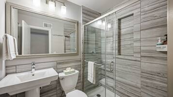 A modern bathroom with a glass-enclosed shower, a white sink, and a large mirror.