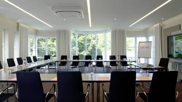 Una sala conferenze con un lungo tavolo, sedie nere e una lavagna.
