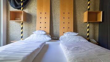A hotel room with two beds, wooden headboards, and striped poles.