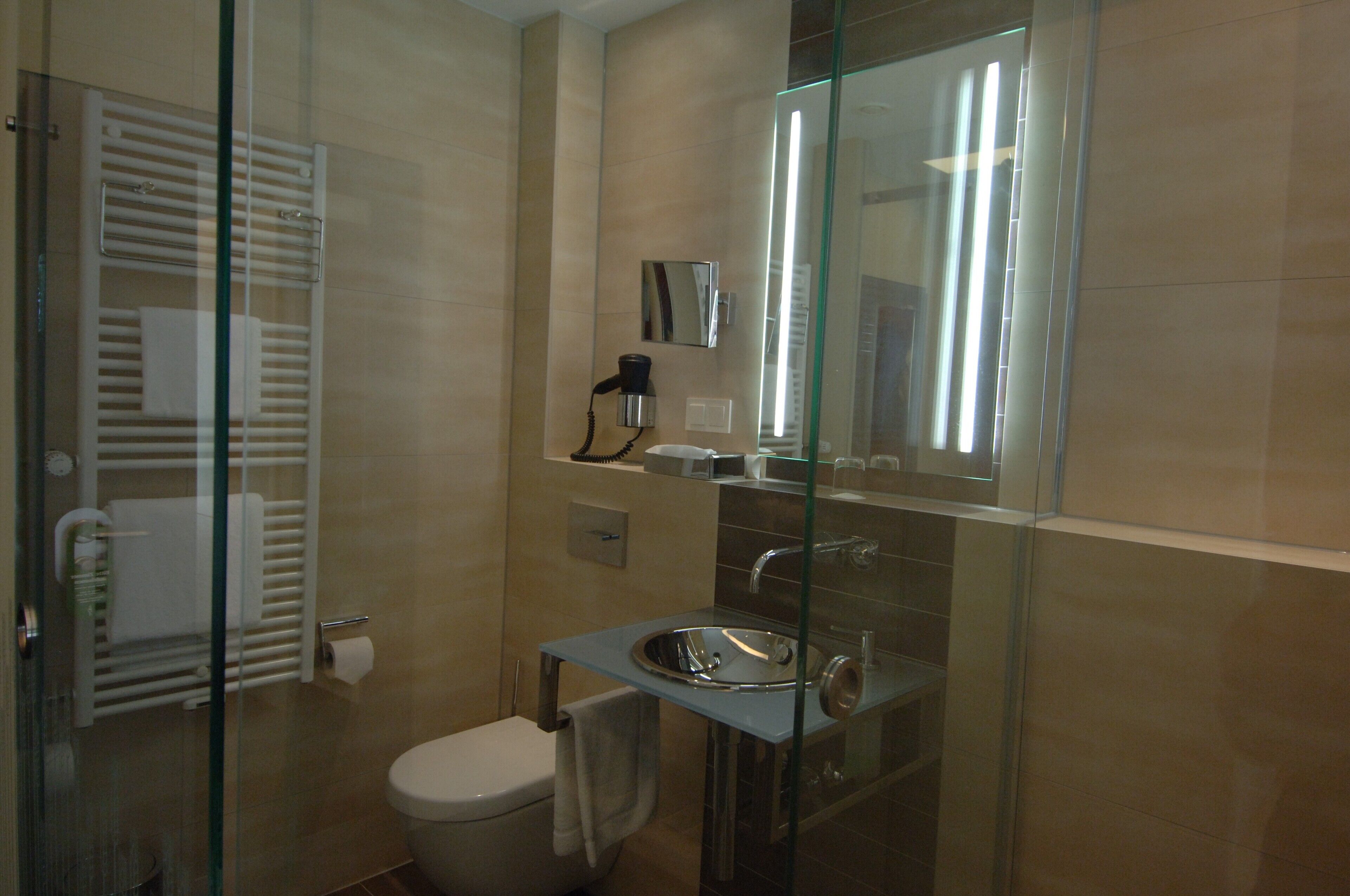 A modern bathroom with a glass shower enclosure, a built-in sink, and a toilet.