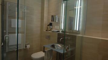 A modern bathroom with a glass shower enclosure, a built-in sink, and a toilet.