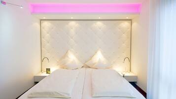 A modern hotel room with a tufted headboard, two bedside tables with lamps, and a neutral color scheme.