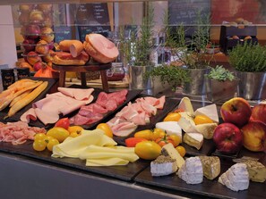 Una presentación de quesos y embutidos con diversas variedades de queso, carne y frutas.