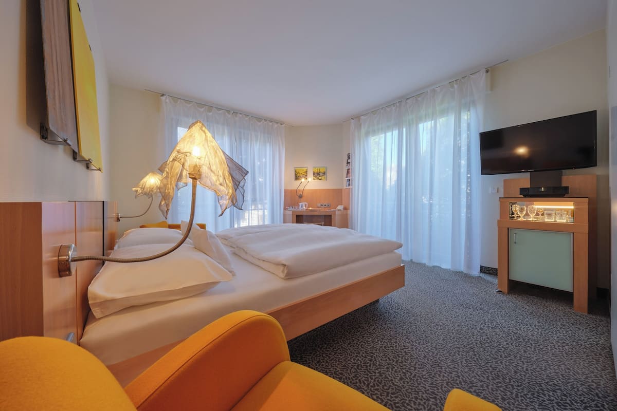 Habitación de hotel con cama, escritorio, televisión y lámpara.
