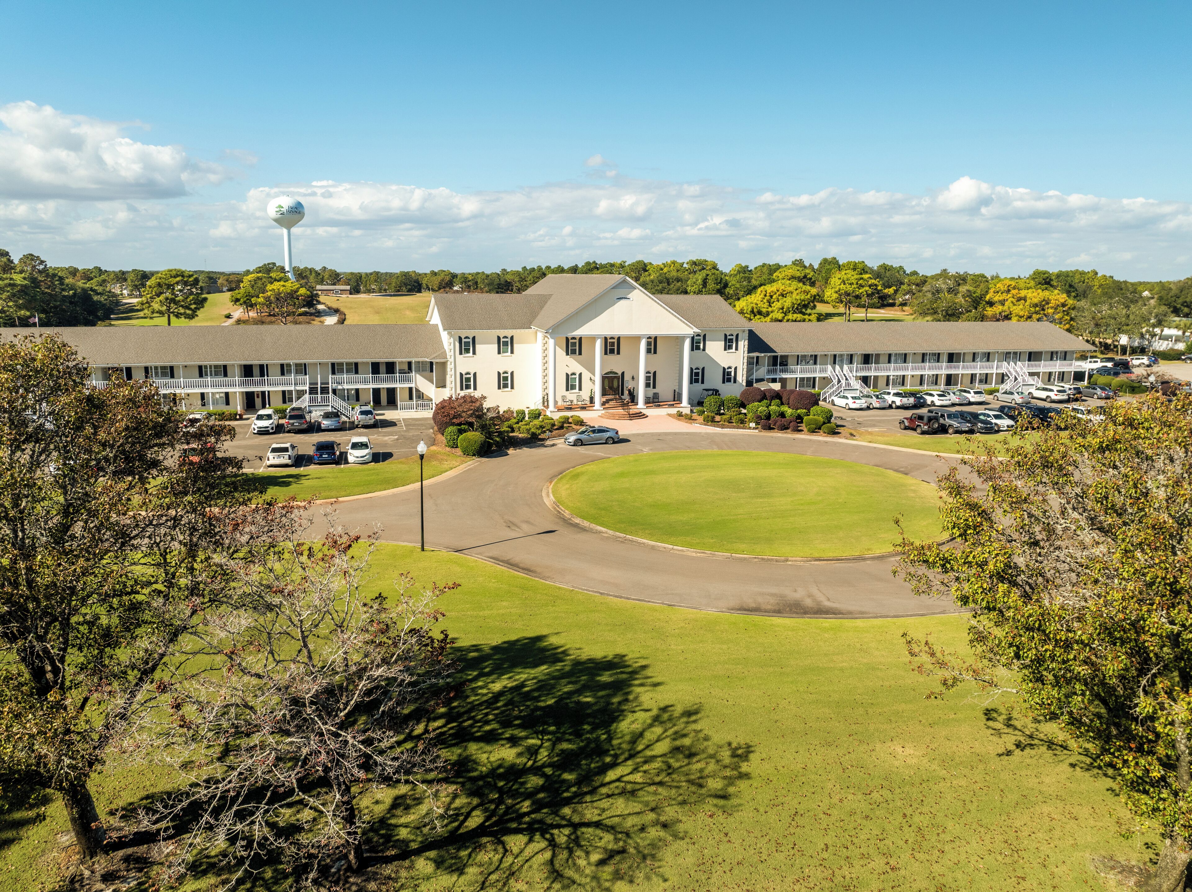 A large building with a central lawn, multiple parking lots, and a prominent water tower.