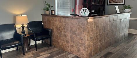 A reception area with a tiled counter, a black leather sofa, a lamp, and a clock on the wall.