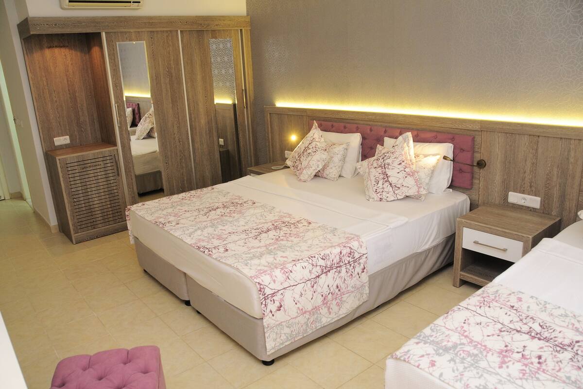 Une chambre d’hôtel avec un grand lit, une table de chevet, une commode, une armoire et un miroir.