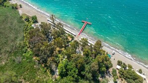 Vista aérea de una zona costera con playa, una estructura roja y vegetación densa.