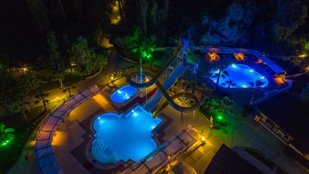 Un parque acuático con múltiples toboganes y piscinas, rodeado de árboles y senderos.