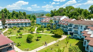 Un resort con edificios de varios pisos, un césped bien cuidado y una vista despejada de montañas al fondo.