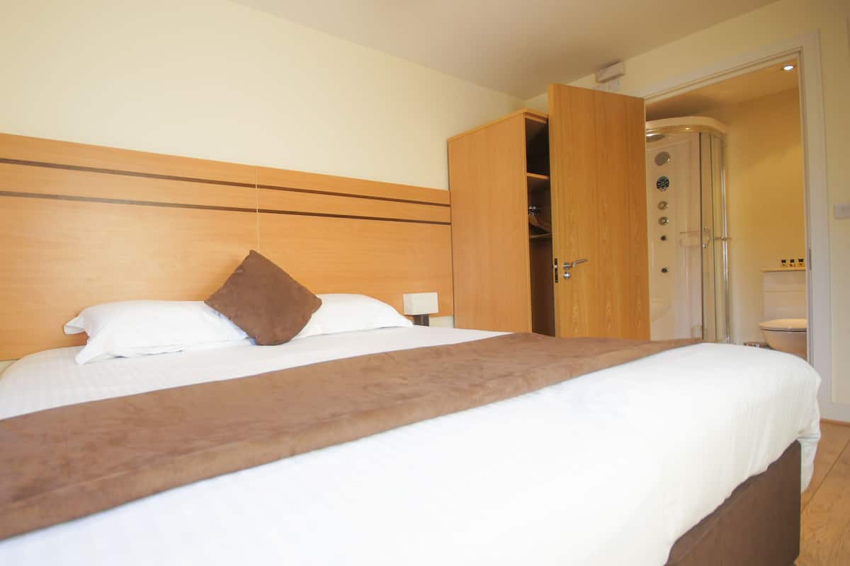A hotel room with a large bed, wooden headboard, and a wardrobe with a mirror.