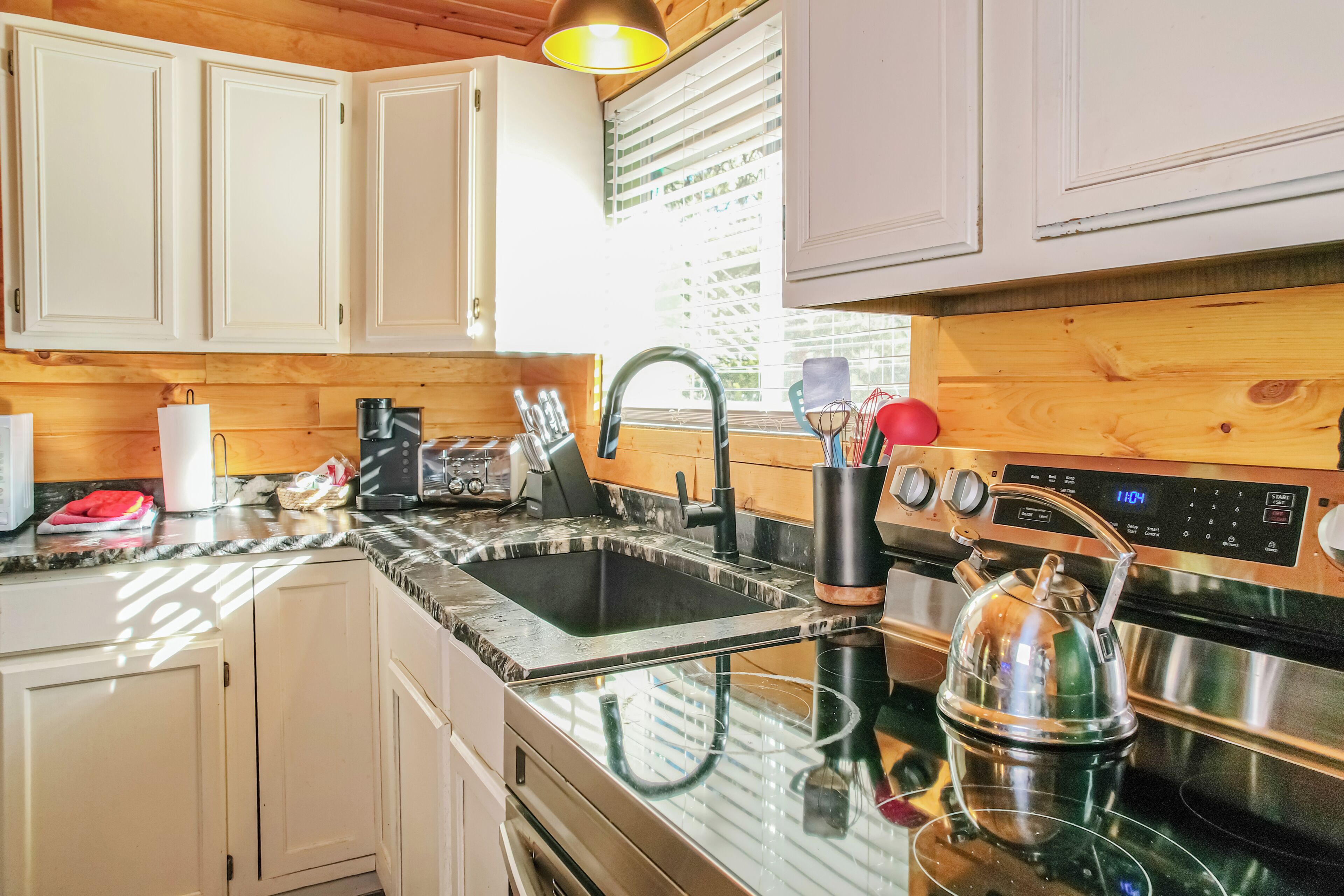Una cocina moderna con estufa de acero inoxidable, un lavamanos y armarios de madera.