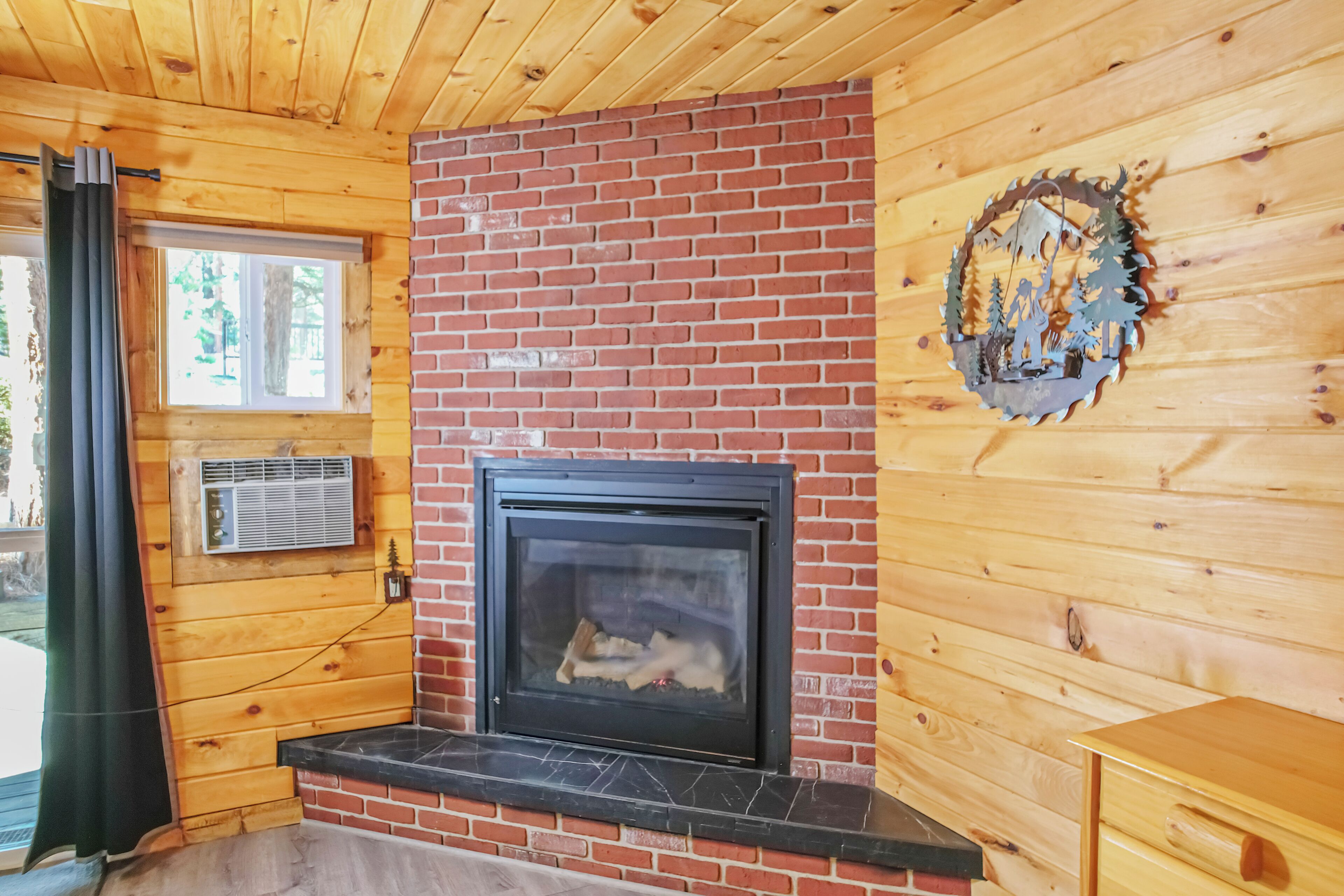 Interior de una cabaña de madera con chimenea, una ventana y una puerta.