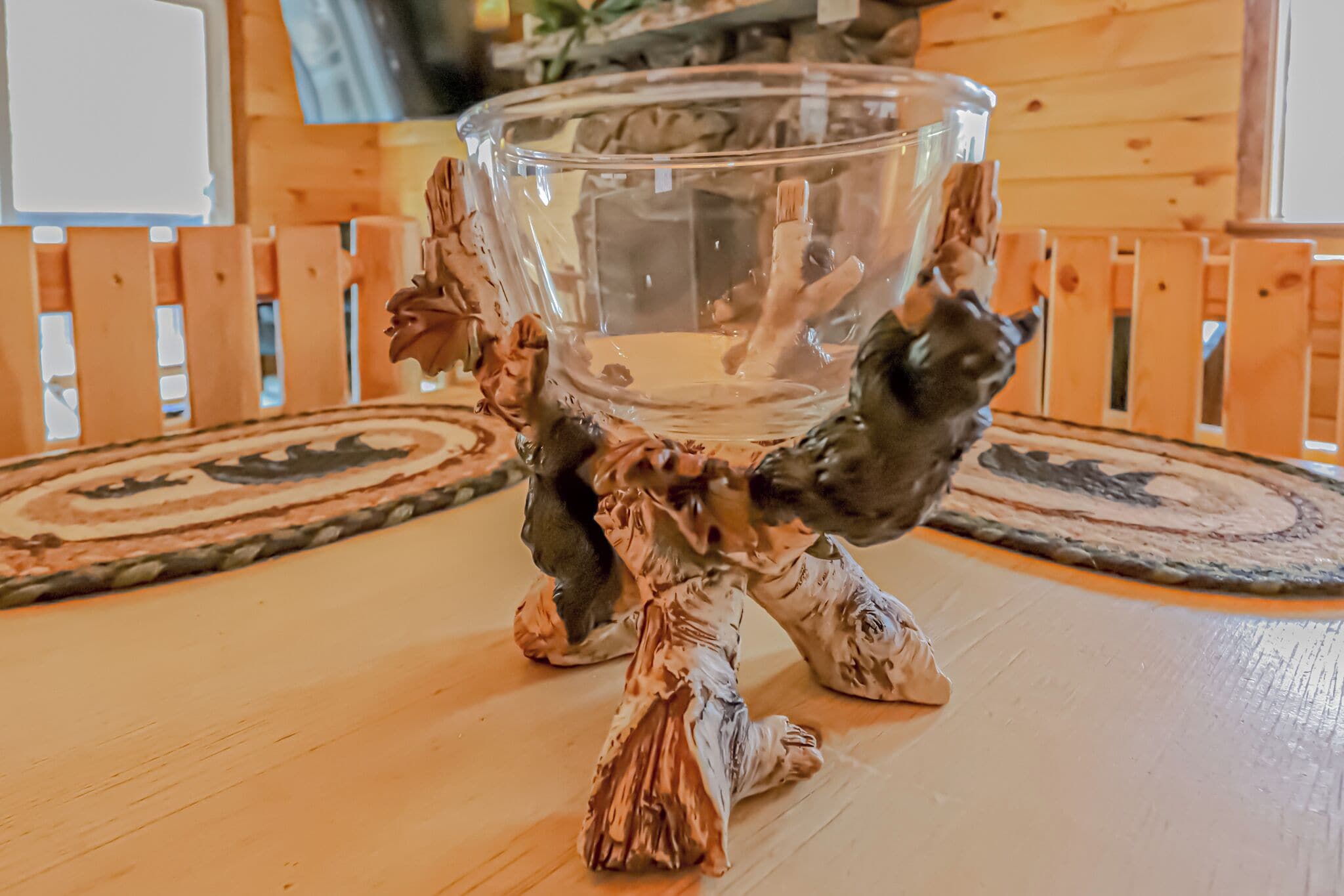 A wooden table with a glass bowl on a decorative stand.
