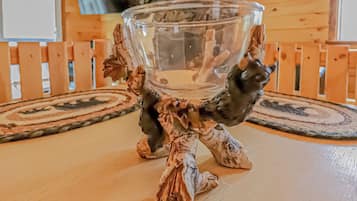 A wooden table with a glass bowl on a decorative stand.