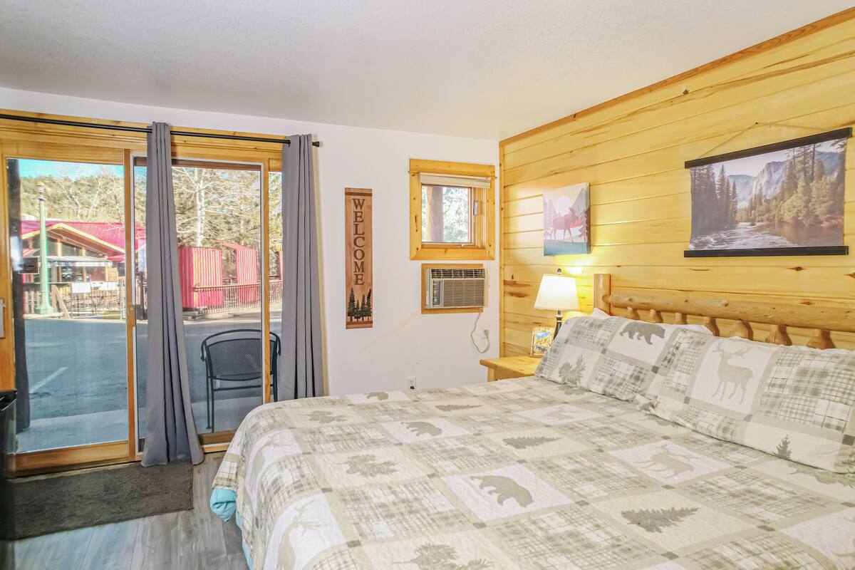 A bedroom with a bed, a window, a door, a wall-mounted picture, and a welcome sign.