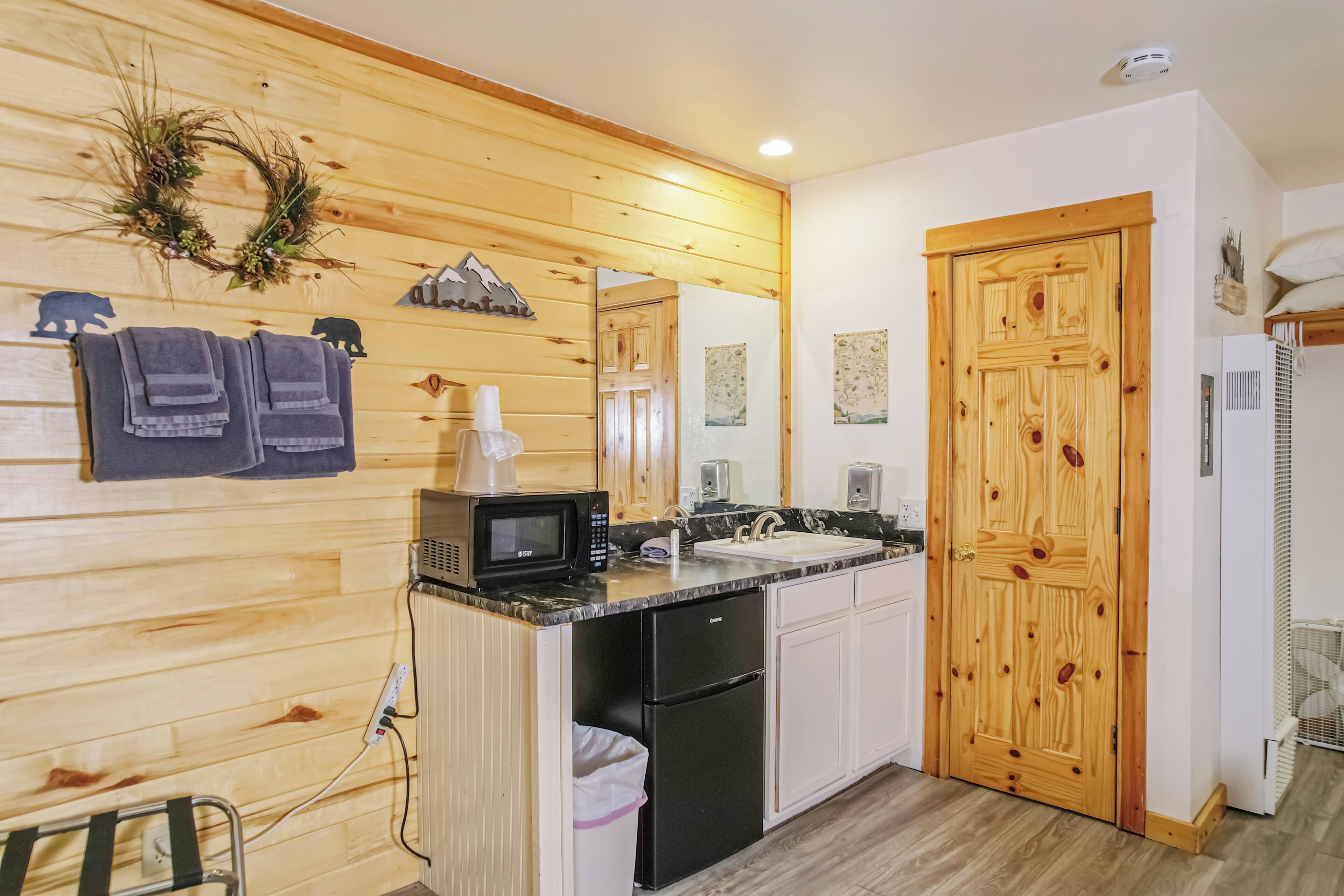 Una cocina con paredes de madera, microondas, fregadero y refrigerador.