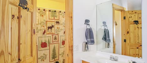 A bathroom with wooden cabinetry, a white sink, and a mirror.