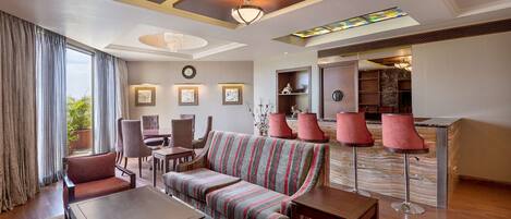 A modern hotel lobby with a sofa, chairs, a dining table, and a bar area.