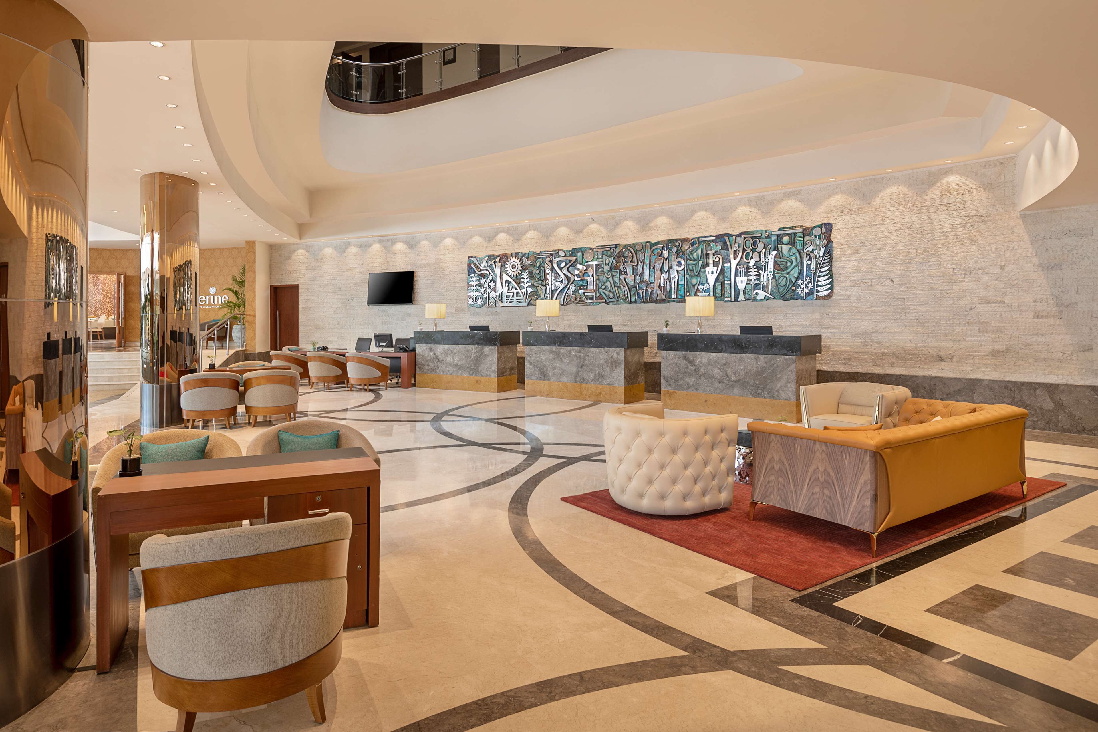 A lobby with a reception desk, seating area, and a large abstract art piece on the wall.