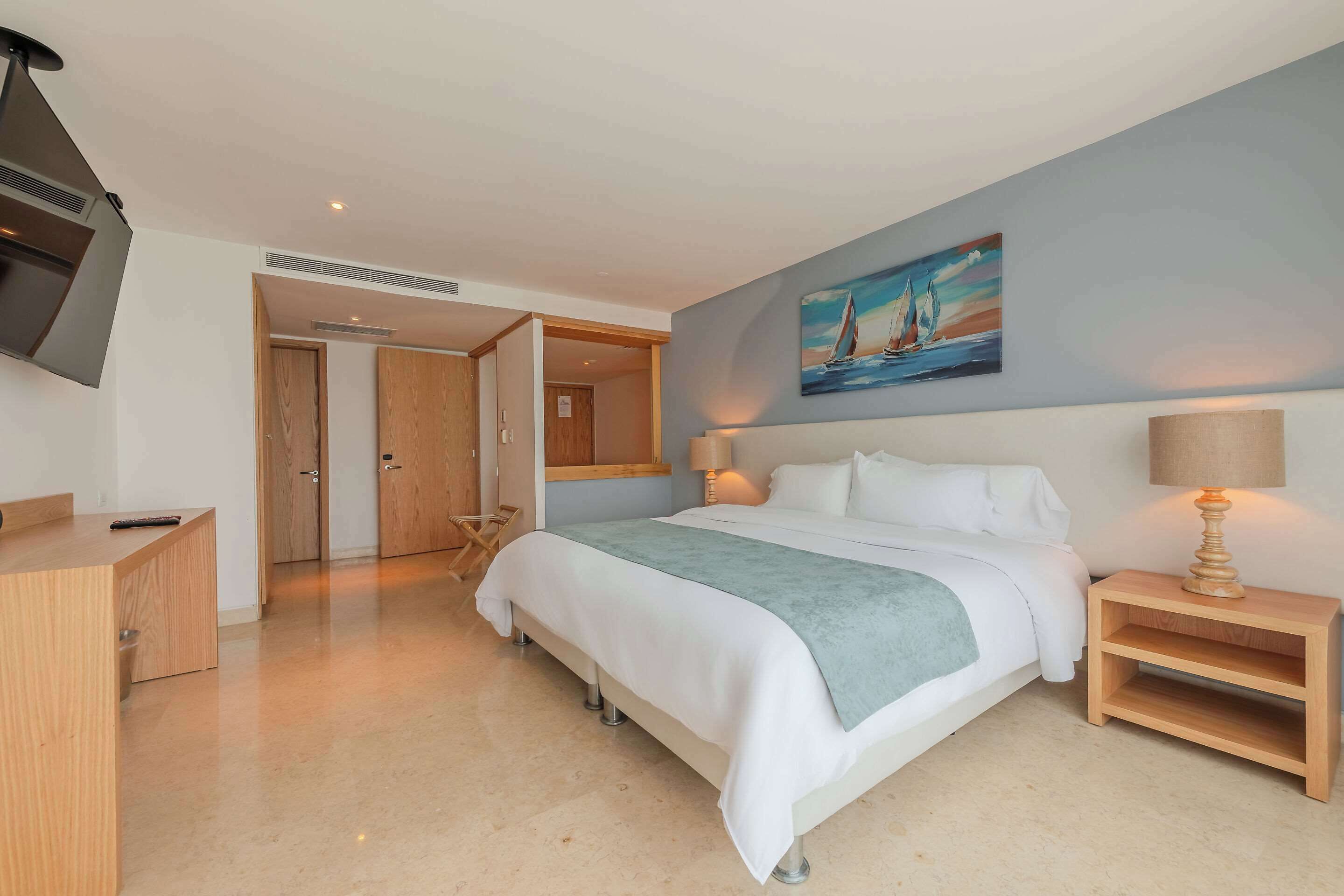 A modern bedroom with a bed, bedside table, and a painting on the wall.