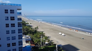 Un hotel frente a la playa con piscina, sombrillas y vistas al océano.