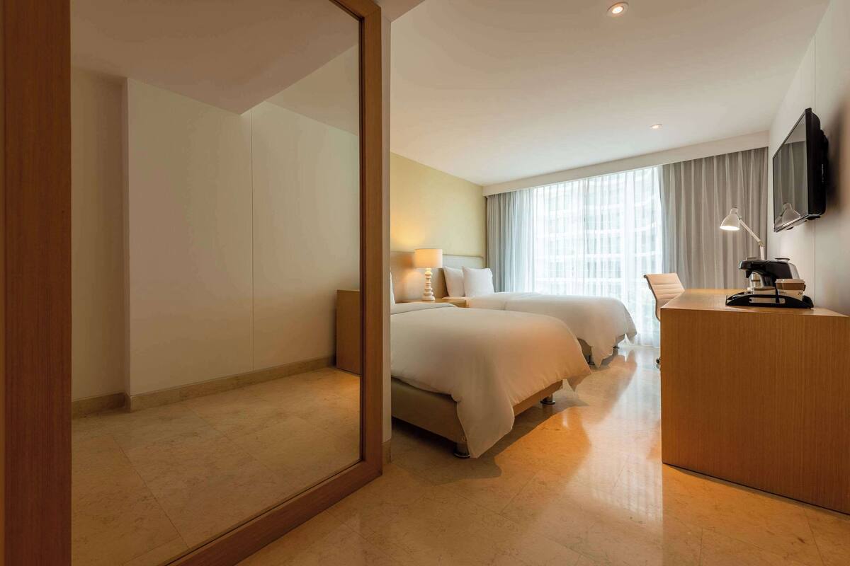 Une chambre d’hôtel avec un grand lit, un bureau, un miroir et une télévision.