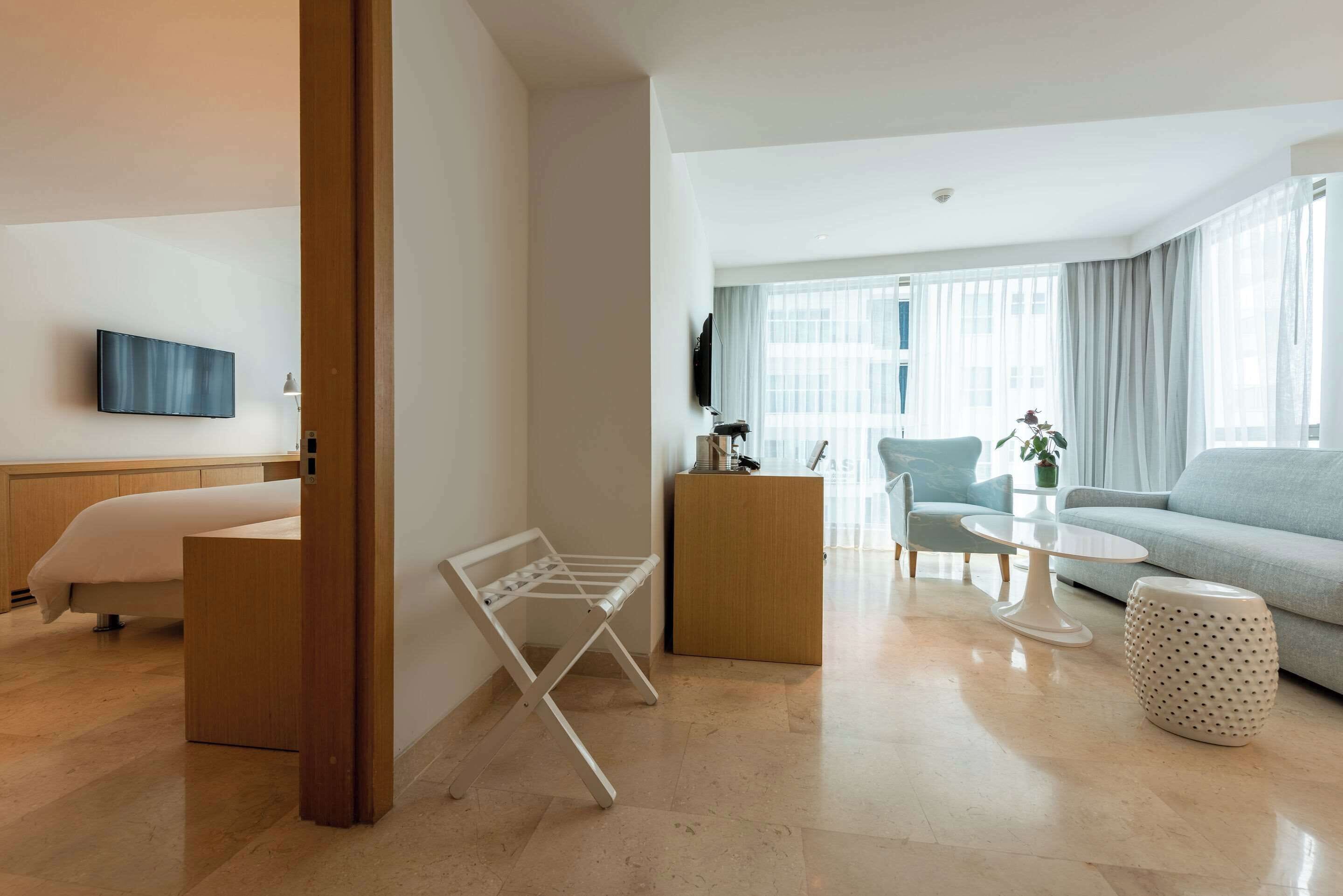 A modern living room with a sofa, a coffee table, a TV mounted on the wall, and a wooden cabinet.