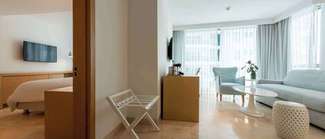 A modern living room with a sofa, a coffee table, a TV mounted on the wall, and a wooden cabinet.